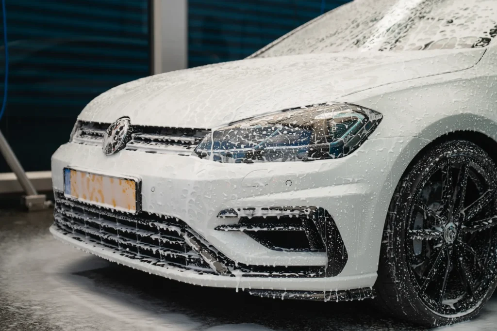 Witte Volkswagen Golf 7.5R onder het wasschuim tijdens een premium wasbeurt